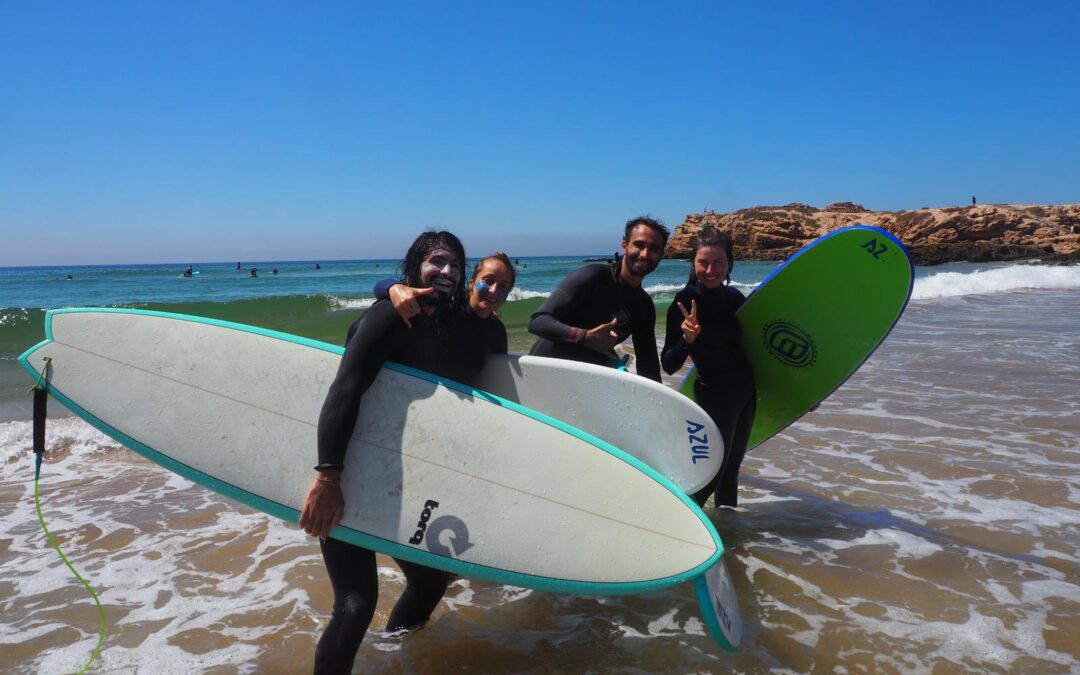 Surfers standing on the beach with their surfboards in hand, enjoying the sunny day after a surfing session in Tamraght, near Taghazout, Morocco.