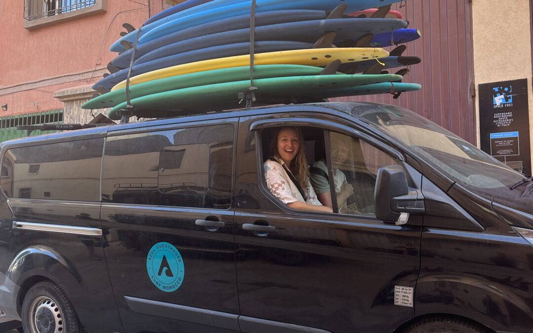 Voiture d'Azul Guesthouse avec des clients à bord et des planches de surf sur le toit, se dirigeant vers la plage depuis le surf camp.