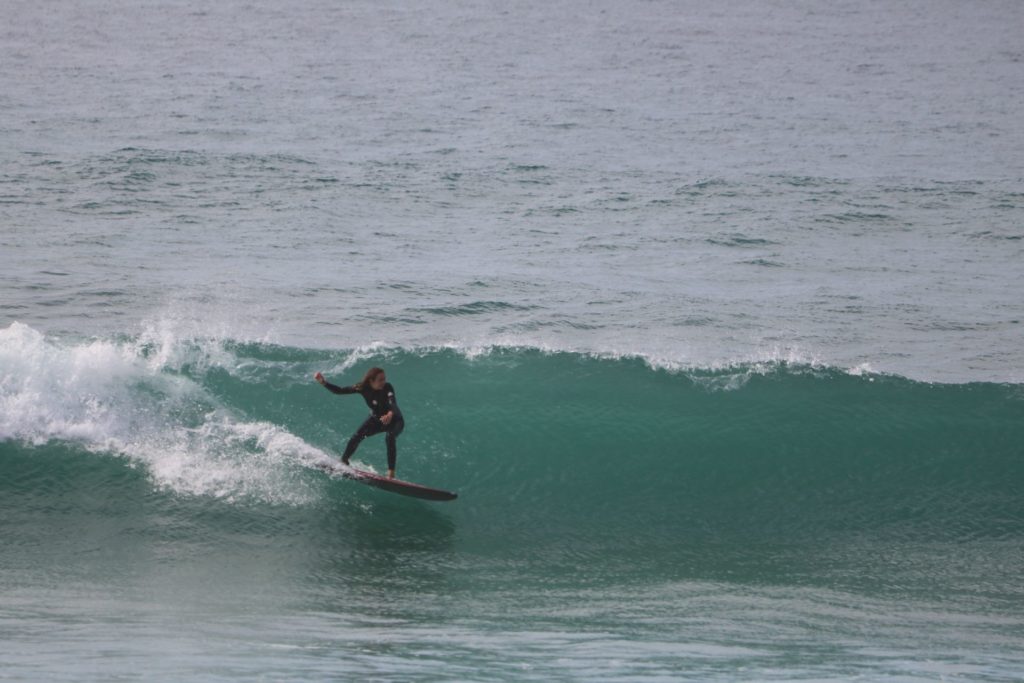 A female surfer riding a wave at KM 17, a popular spot for beginners in Morocco.