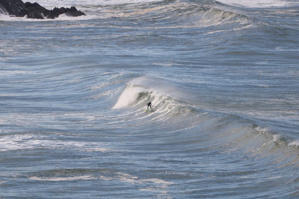 Un surfeur en stand up paddle prend une belle vague à Mirleft