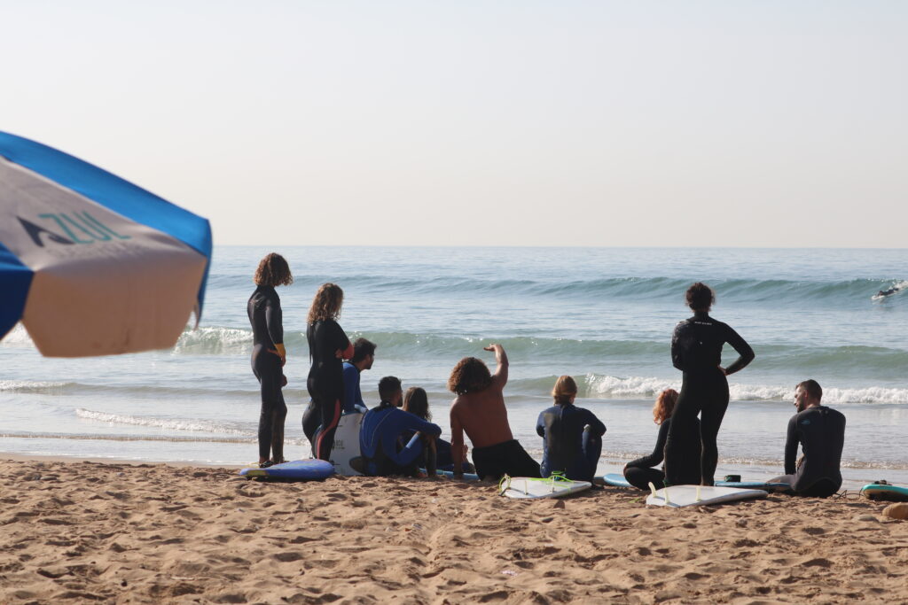 Groupe de surfeurs recevant des instructions d'un moniteur de surf à Banana Point au Maroc