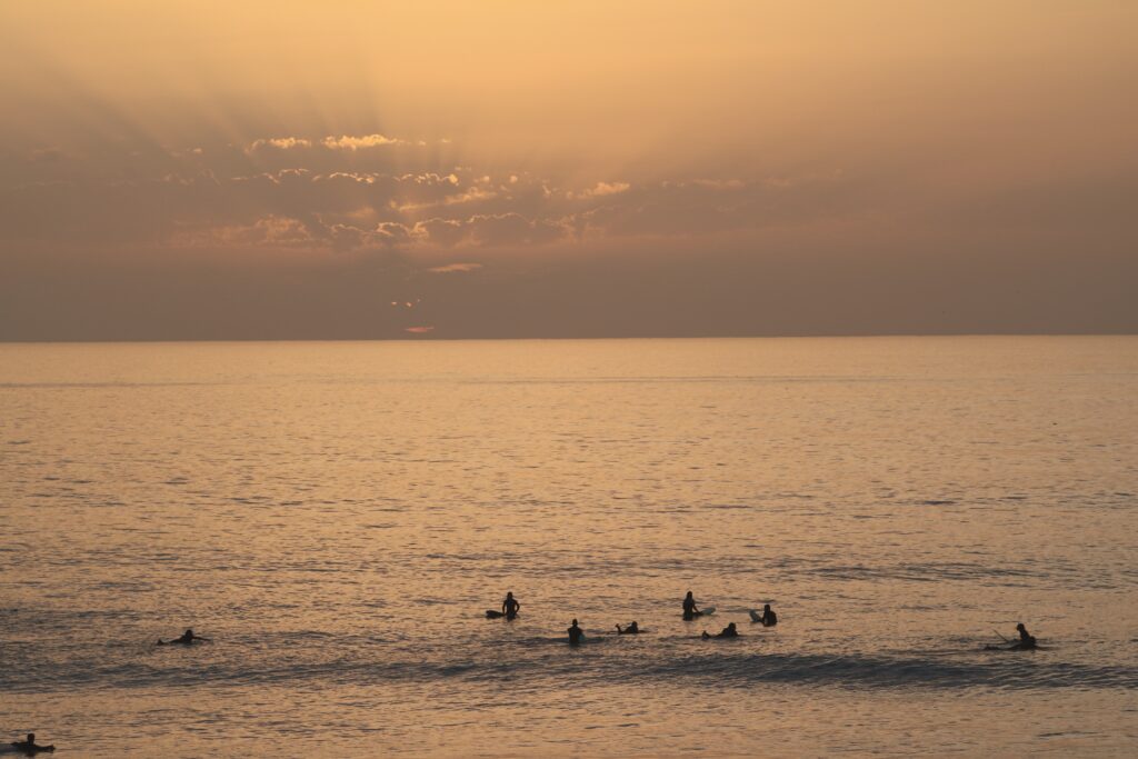 Sunset on the beach with surfers in the background, in Morocco