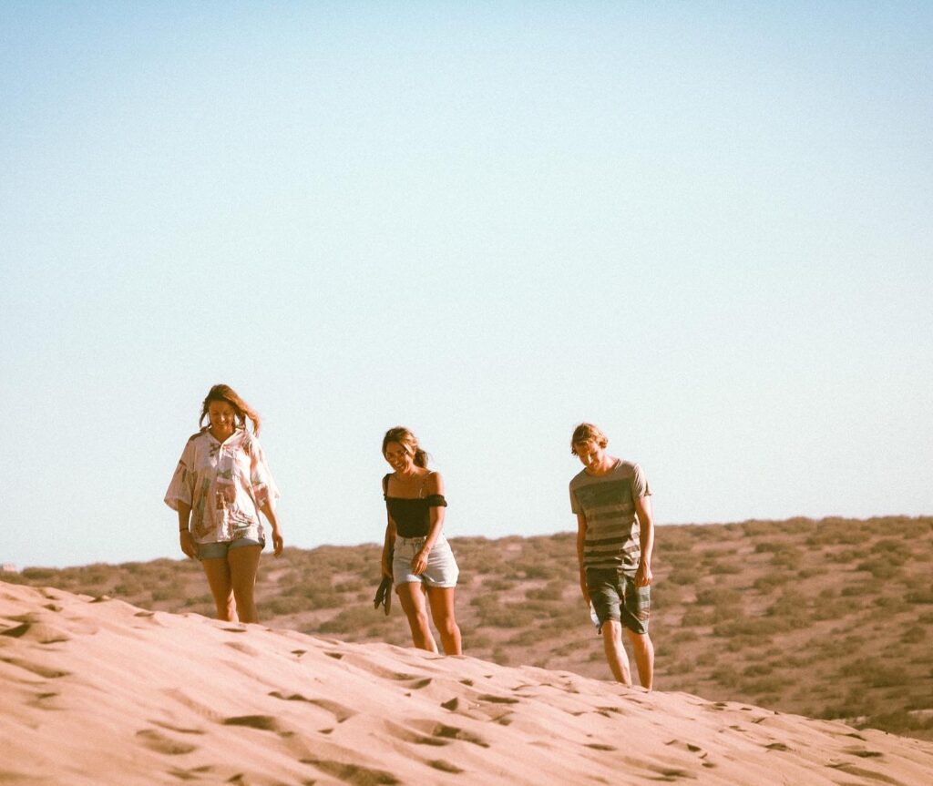 Excursion to the dunes of Tamri, Morocco, with visitors walking on the large sand dunes under a clear blue sky.