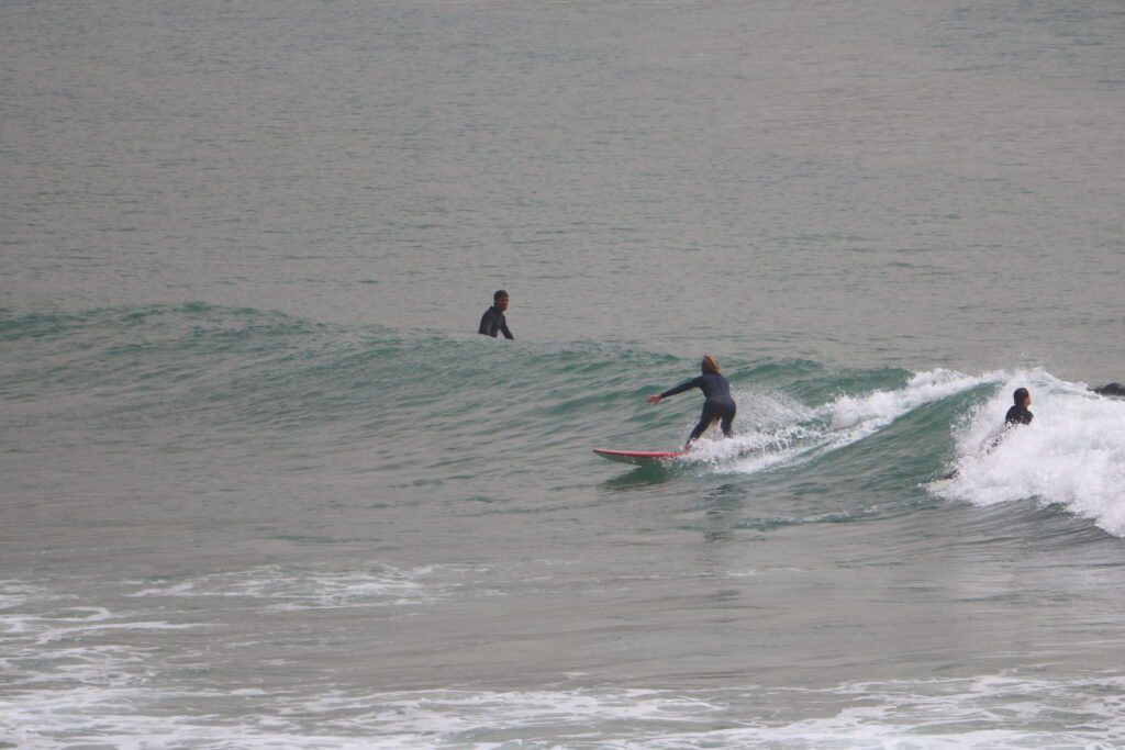 An intermediate surfer gliding smoothly on a beautiful wave in Imsouane Bay, Morocco, known for its long and perfect waves.